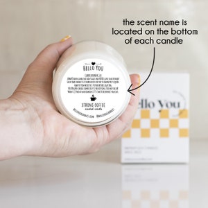 May include: A white candle jar with a black label that reads "HELLO YOU" and "STRONG COFFEE scented candle". The scent name is located on the bottom of each candle.