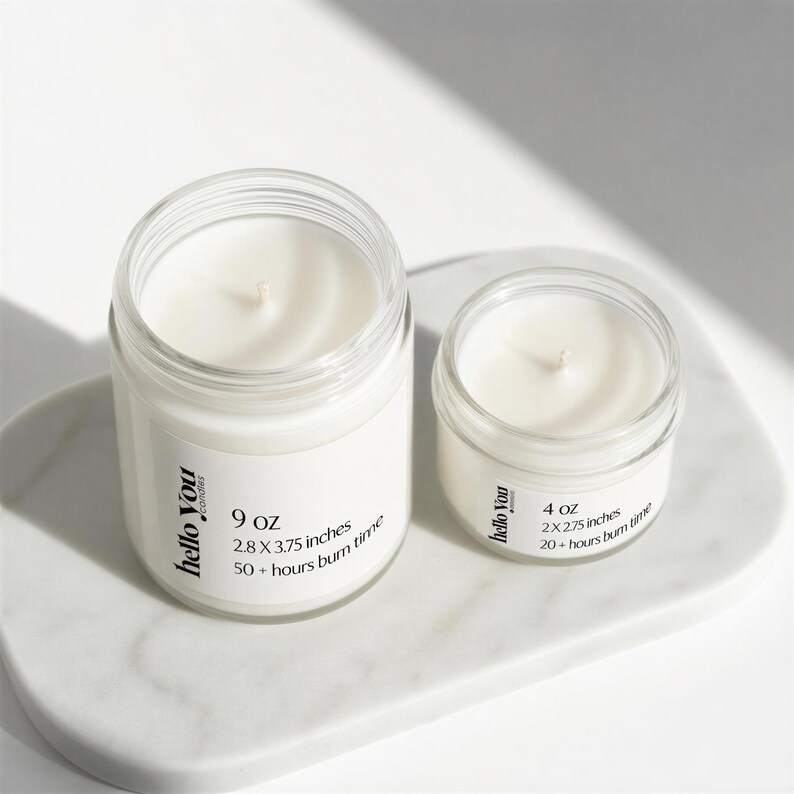 Two candles of different sizes are placed on a white surface, with one candle being larger than the other.
