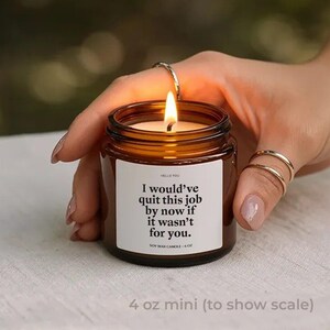 May include: A lit soy wax candle in a small amber glass jar. The candle has a white label with the text "I would've quit this job by now if it wasn't for you." The candle is 4 oz.