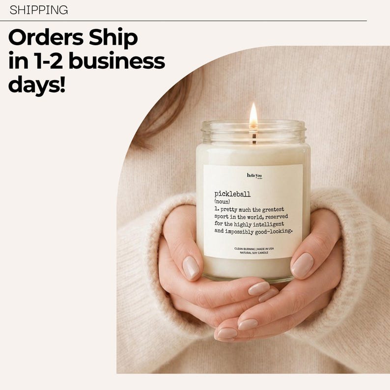 A person's hands holding a lit candle with a label that says "pickleball" and a definition of the word.