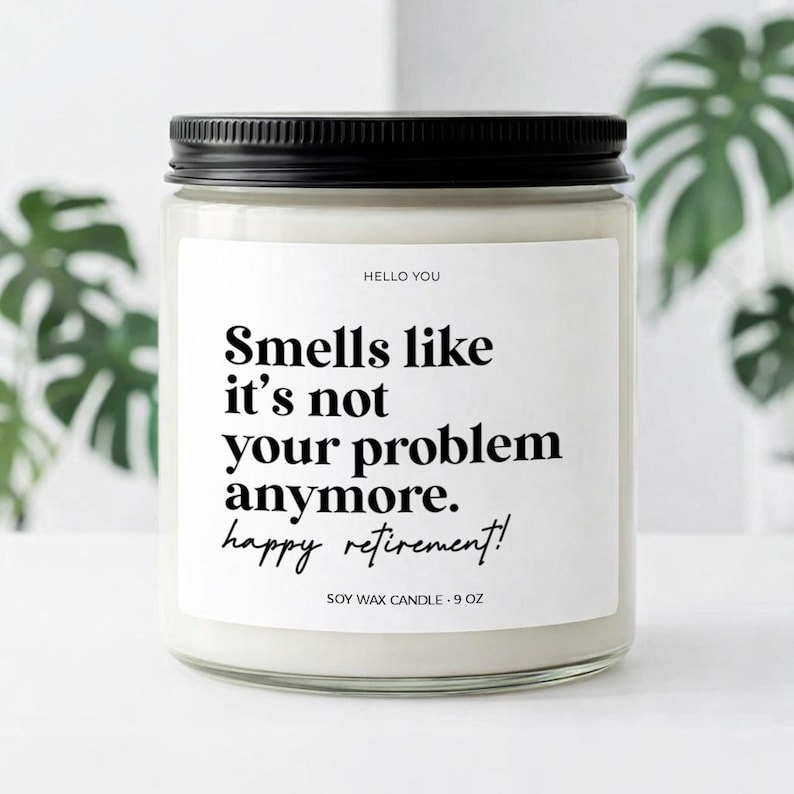May include: A soy wax candle in a clear glass jar with a black lid. The label reads "Smells like it's not your problem anymore. happy retirement!" in black text. The candle is 9 oz.