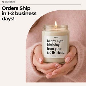 A person holding a lit candle labeled "Happy 29th Birthday from your 110 lb friend" against a pink background.
