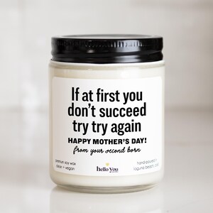 May include: A white candle with a black lid and a label that reads "If at first you don't succeed try try again Happy Mother's Day! from your second born". The candle is made with premium soy wax and is clean and vegan. It is hand-poured in Laguna Beach, California.