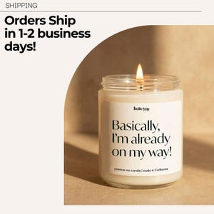 a lit candle in a jar, with a label that reads "Basically, I'm already on my way!" The background is a light brown color, and there is text at the top and bottom of the image.