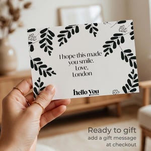 A person's hand holding a card with a floral design and text on it.