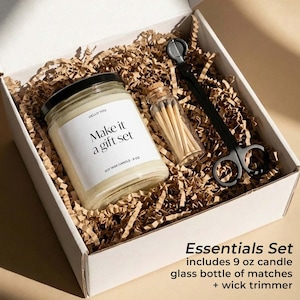 May include: A white gift box filled with brown crinkle paper, containing a candle, a glass bottle of matches, and a black wick trimmer. The candle jar has a black lid and a label that reads "Make it a gift set". The set includes a 9 oz candle.