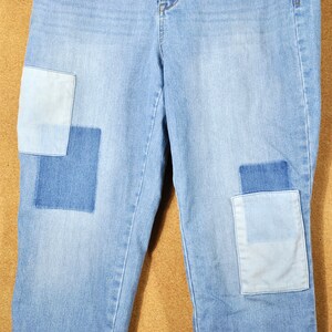May include: Light blue denim jeans with two large patches on the knees. Each patch is made of different shades of blue denim.