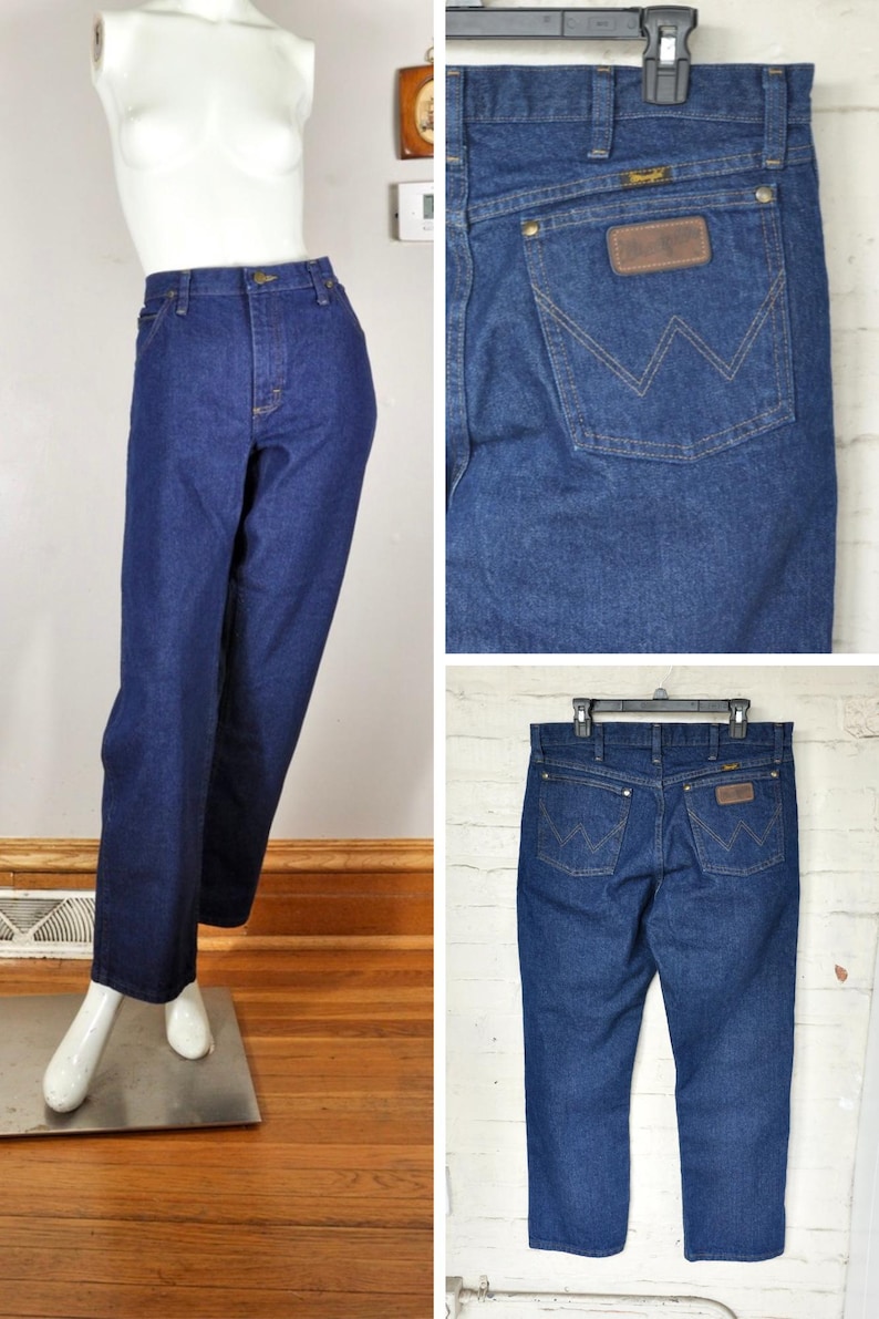 May include: Dark blue denim jeans with a classic straight leg fit. The jeans feature a brown leather patch on the back pocket with the brand logo and a signature 'W' stitching design. The jeans are displayed on a mannequin.