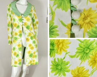 May include: A vintage floral print coat on a mannequin. The coat features a white background with yellow and green flower patterns. It has a light green collar and large white buttons. The coat is knee-length.