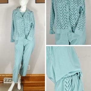 May include: A pale blue two-piece outfit displayed on a mannequin. The outfit comprises a button-up jacket with an openwork pattern and matching trousers. The jacket has long sleeves and a collar. The trousers are straight-legged.