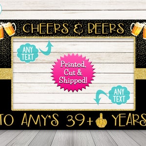 May include: Black photo booth frame with gold glitter accents and the text "CHEERS & BEERS" at the top. The frame has two blank spaces for text, one at the top and one at the bottom. The bottom text reads "TO AMY'S 39+ YEARS".