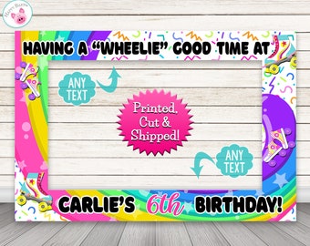 May include: A colorful photo booth frame with a rainbow design and roller skate graphics. The text "HAVING A "WHEELIE" GOOD TIME AT" is at the top of the frame. The text "CARLIE'S 6th BIRTHDAY!" is at the bottom of the frame. There are two blank spaces for text.