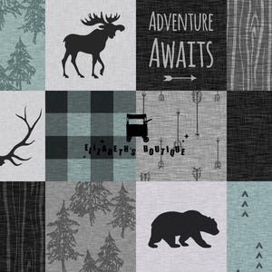 May include: A black and white quilt with a woodland theme. The quilt features a moose, antlers, a bear, trees, and the text "Adventure Awaits".