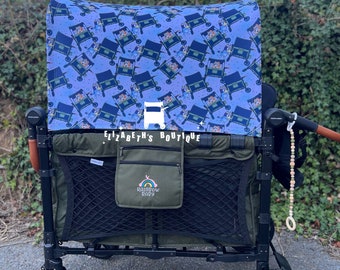 May include: A green and black wagon with a patterned canopy featuring a cartoon character design. The wagon has black wheels, a mesh storage area, and a small pocket with the text "Rainbow Baby". The text "Elizabeth's Boutique" is visible.