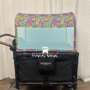 May include: A black wagon with a rainbow leopard print canopy and a mesh window. The wagon has a Wonderfold logo and the text "Elizabeth's Boutique" on the side.
