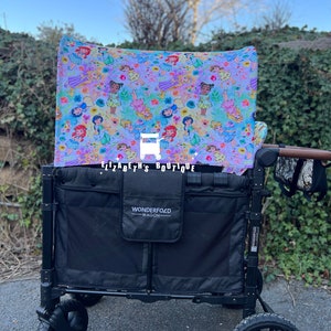 May include: A black wagon with a canopy featuring a colorful print of Disney princesses. The canopy is labeled "Elizabeth's Boutique". The wagon has a black Wonderfold label and a black mesh storage area.