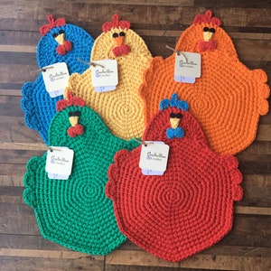 May include: Six crocheted chicken-shaped pot holders in various colors, including blue, yellow, orange, green, and red. Each pot holder has a small crocheted bow and a tag that reads "Gallon Bore Crochet".