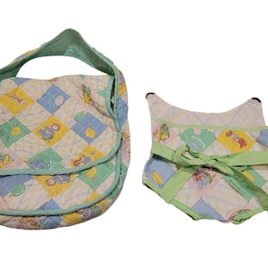 Può includere: Una borsa in tessuto trapuntato e una bavaglino in tessuto trapuntato abbinato con un motivo a rombi nei colori pastello giallo, blu e verde. La borsa ha una chiusura a patta e un bordo verde menta. Il bavaglino ha un nastro verde menta.
