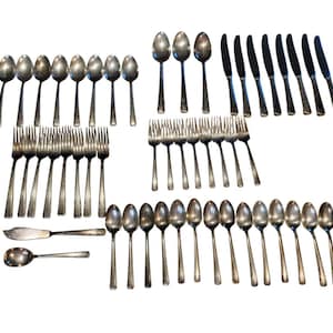 May include: A set of silverware, including forks, spoons, and knives, all made of silver. The silverware is arranged in rows on a white background.