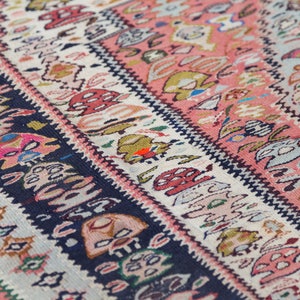 May include: Close-up of a colourful woven rug with intricate patterns in shades of pink, blue, green, and white.