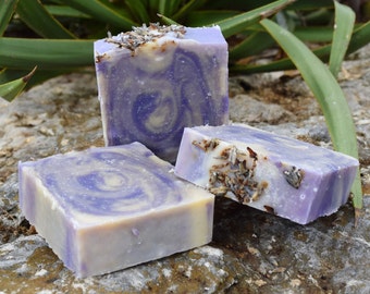May include: Three bars of handmade lavender soap. The soap is a swirl of purple and white with dried lavender flowers embedded in the top bar.
