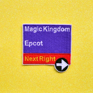 May include: A purple and red embroidered patch with the text "Magic Kingdom" and "Epcot" in white. The bottom of the patch is red and says "Next Right" with a black circle and white arrow pointing to the right.