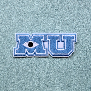 May include: A light blue embroidered patch featuring the letters "MU" in a collegiate style. The "M" incorporates an eye with a black pupil. The patch has a white border and is set against a light blue glitter background.