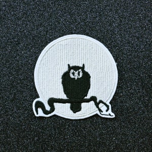 May include: White felt patch with an embroidered black owl perched on a branch in front of a white moon.