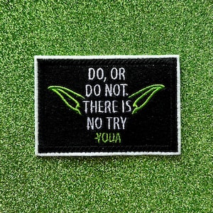 May include: A black rectangular patch with a white border featuring the quote "Do, or do not. There is no try. Yoda" in white text. The patch includes green stylized leaf shapes. The background is a glittery green.