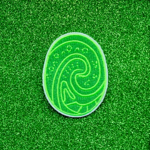 May include: Green and white embroidered patch with a swirling wave design. The patch is shaped like an oval and has a white border.