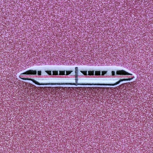 May include: A white and red embroidered patch of a monorail train on a pink glitter background.
