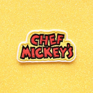 May include: A yellow, red, and black embroidered patch with the text "Chef Mickey's".