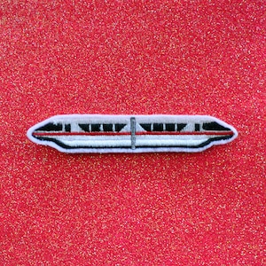 May include: A white and red embroidered patch of a monorail train on a red glitter background.