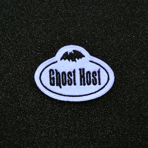 May include: A purple embroidered patch with a black bat and the text "Ghost Host" in black.