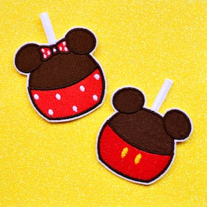 May include: Two embroidered iron-on patches featuring a red and white Mickey Mouse head and a Minnie Mouse head with a red bow. The patches are on a yellow glitter background.