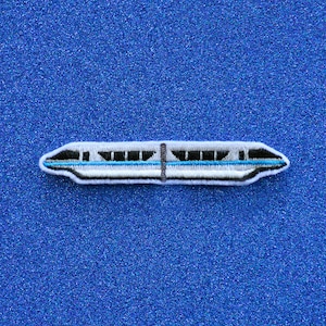 May include: A white and blue embroidered patch of a monorail train. The train has a dark gray stripe running along the side and a light blue stripe running along the bottom.