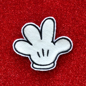 May include: White felt Mickey Mouse glove patch with black stitching and three fingers. The patch is on a red glitter background.