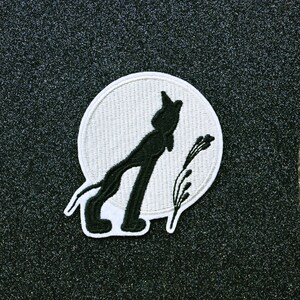 May include: A black silhouette of a wolf howling at the moon, with a white background and a few blades of grass in the foreground.