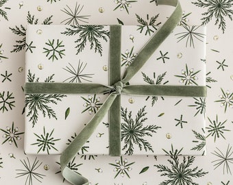 May include: A wrapped gift with a white background featuring a repeating pattern of green botanical illustrations. The gift is tied with a sage green velvet ribbon. The wrapping paper and ribbon create a cohesive, nature-inspired aesthetic.