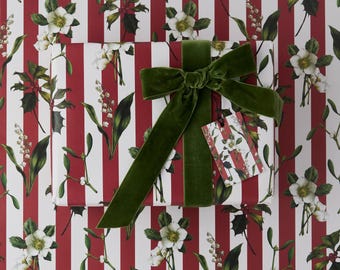 May include: A wrapped gift with a green velvet bow and a matching gift tag. The wrapping paper features a pattern of white flowers and green leaves on a red and white striped background. The gift tag has the same floral pattern.