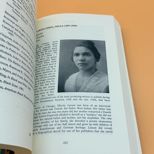 Pu&ograve; includere: Un libro aperto con un ritratto in bianco e nero di Nella Larsen e testo. Il numero di pagina 213 &egrave; visibile. Il libro &egrave; appoggiato su una superficie arancione.