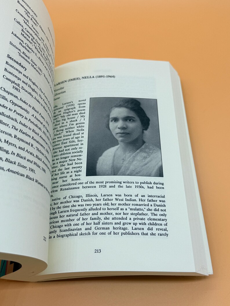 Pu&ograve; includere: Un libro aperto con un ritratto in bianco e nero di Nella Larsen e testo. Il numero di pagina 213 &egrave; visibile. Il libro &egrave; appoggiato su una superficie arancione.