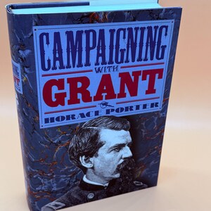 May include: A hardcover book titled "Campaigning with Grant" by Horace Porter. The cover features a portrait of a man in a military uniform and text in blue and red against a dark blue marbled background. The book's spine is visible.