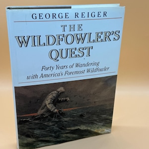 May include: A hardcover book titled "The Wildfowler's Quest" by George Reiger. The cover features a painting of a person in a boat on the water. The book's title and author are in large, bold text.
