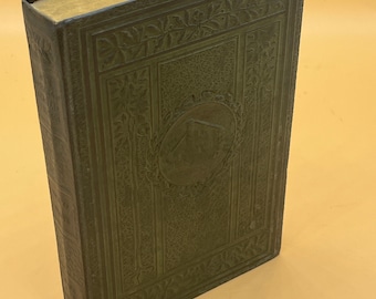 May include: A dark green hardcover book with an embossed floral design and a gold-colored spine. The book has a circular design on the front cover with a raised image of a building.