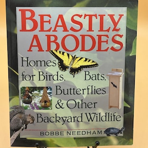 May include: A book titled "Beastly Abodes: Homes for Birds, Bats, Butterflies & Other Backyard Wildlife" by Bobbe Needham. The cover features a yellow and black butterfly, a birdhouse, a bat house, and a squirrel.
