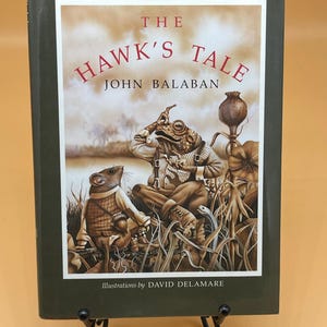 May include: A green hardcover book titled "The Hawk's Tale" by John Balaban. The cover features an illustration of a frog and a mouse in a field.