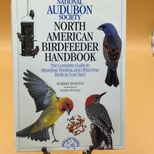 May include: A book titled "North American Birdfeeder Handbook" by the National Audubon Society. The cover features a variety of birds, including a blue grosbeak, a red-bellied woodpecker, and a yellow-rumped warbler.