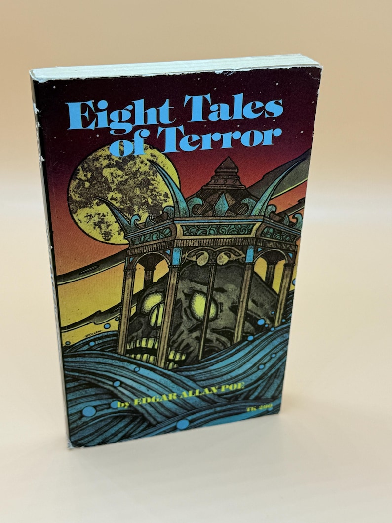 May include: A vintage paperback book titled "Eight Tales of Terror" by Edgar Allan Poe. The cover features a dark, illustrated scene with a skull, a full moon, and stylized waves. The title is in blue text.