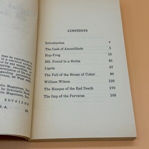 May include: An open book showing the contents page. Titles include "The Cask of Amontillado" and "The Fall of the House of Usher." The book is open on a light beige surface.